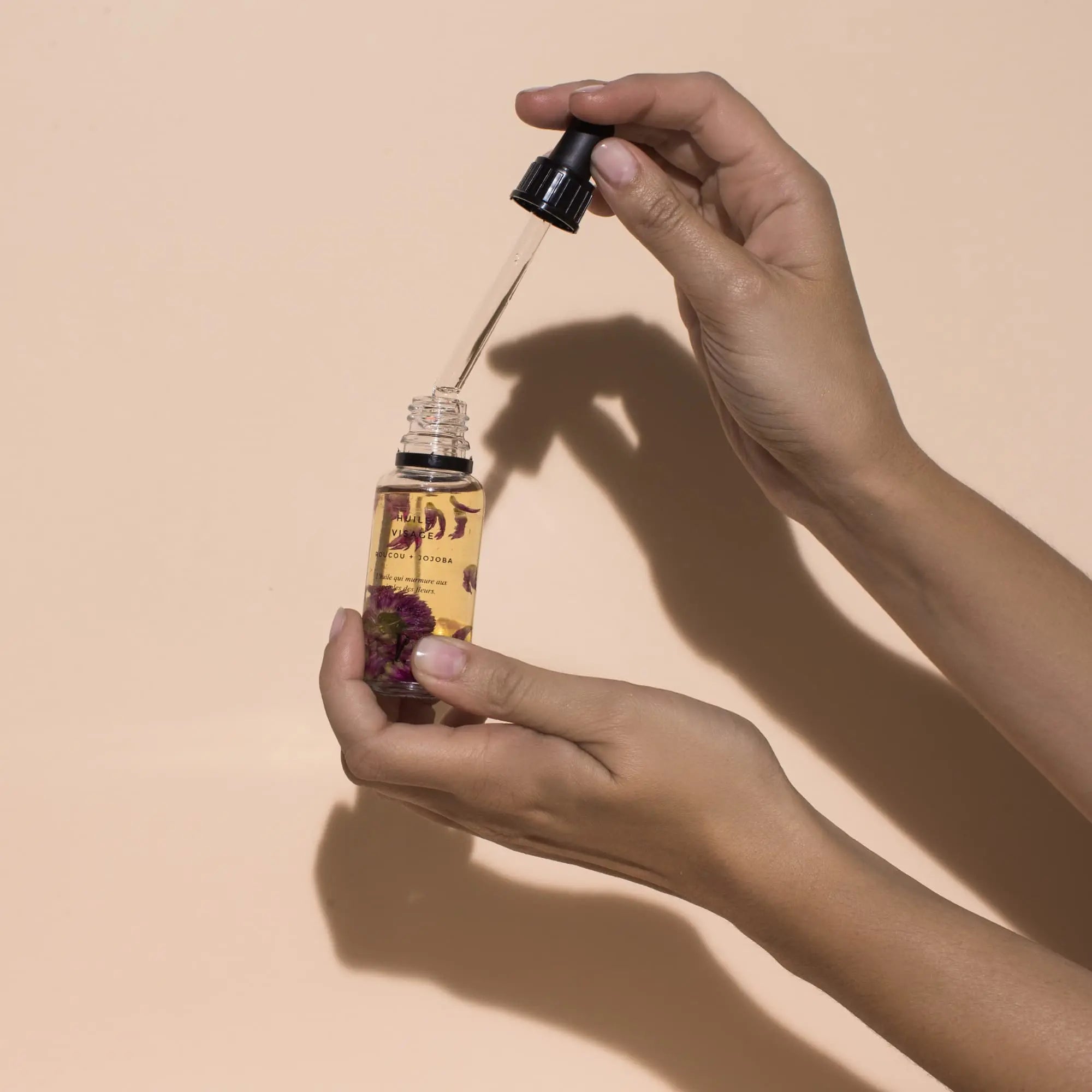 huile visage dans main fond beige