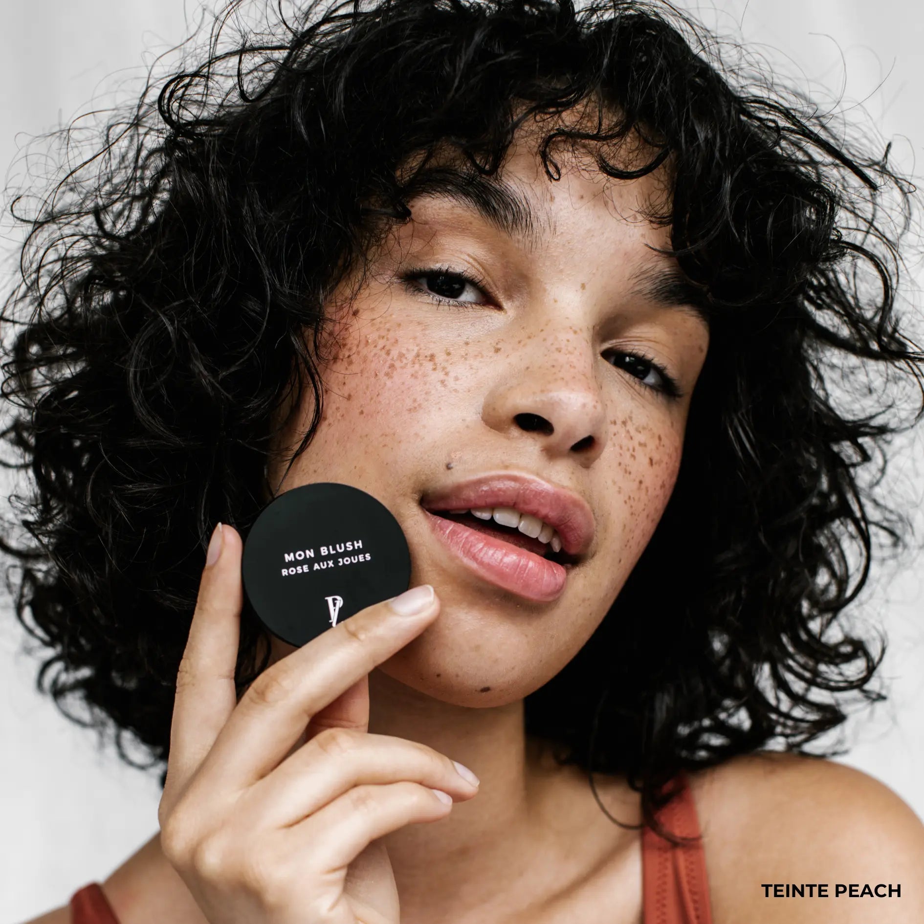 femme tenant blush crème devant son visage