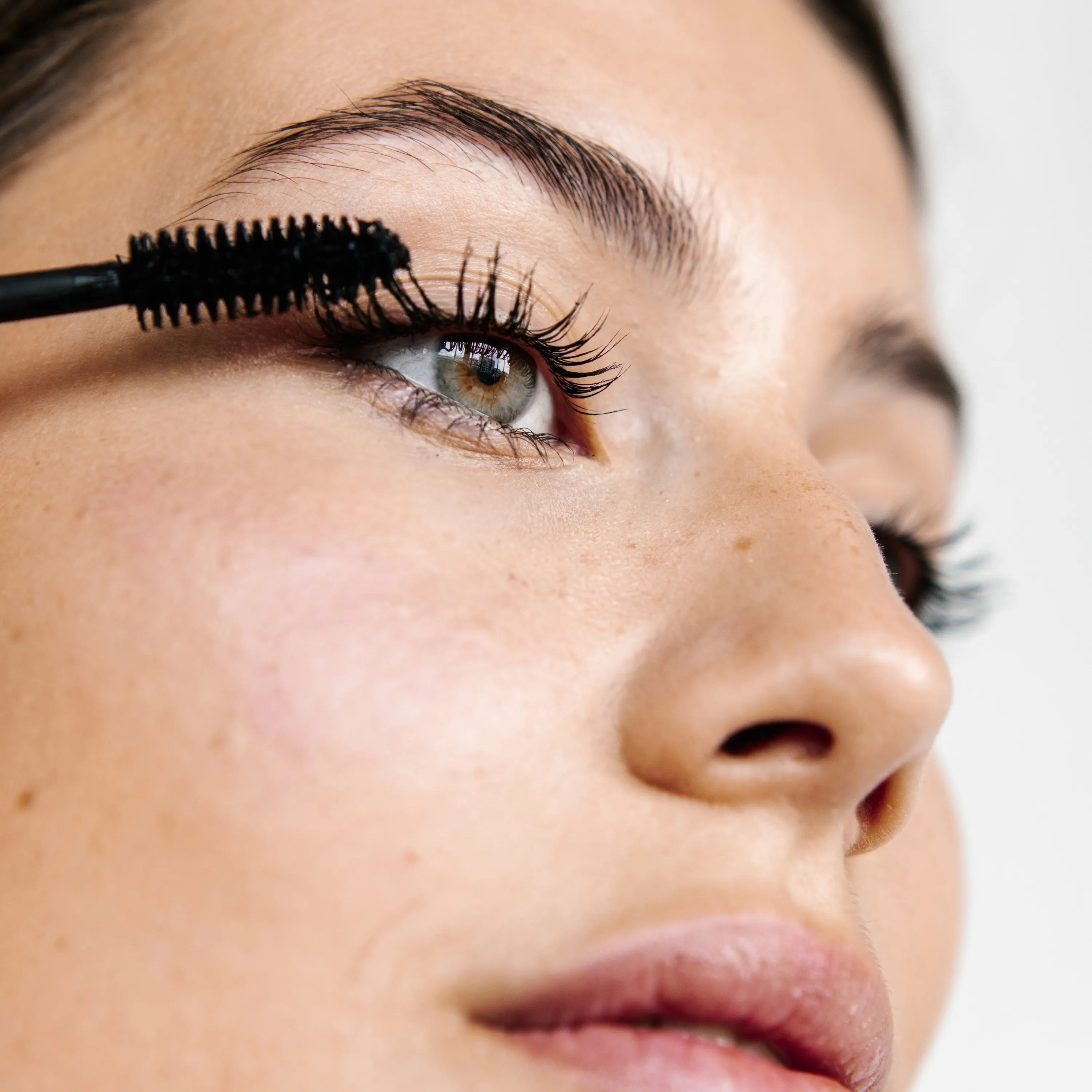 femme appliquant mascara noir sur oeil