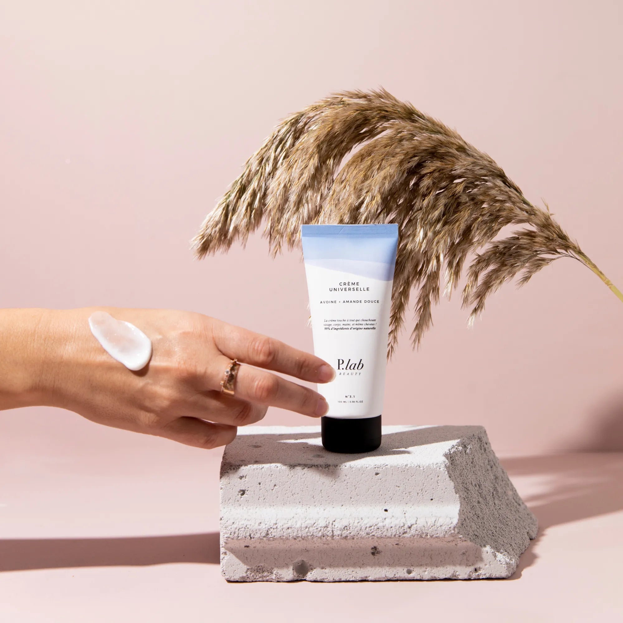 crème universelle sur main fond rose et pampa