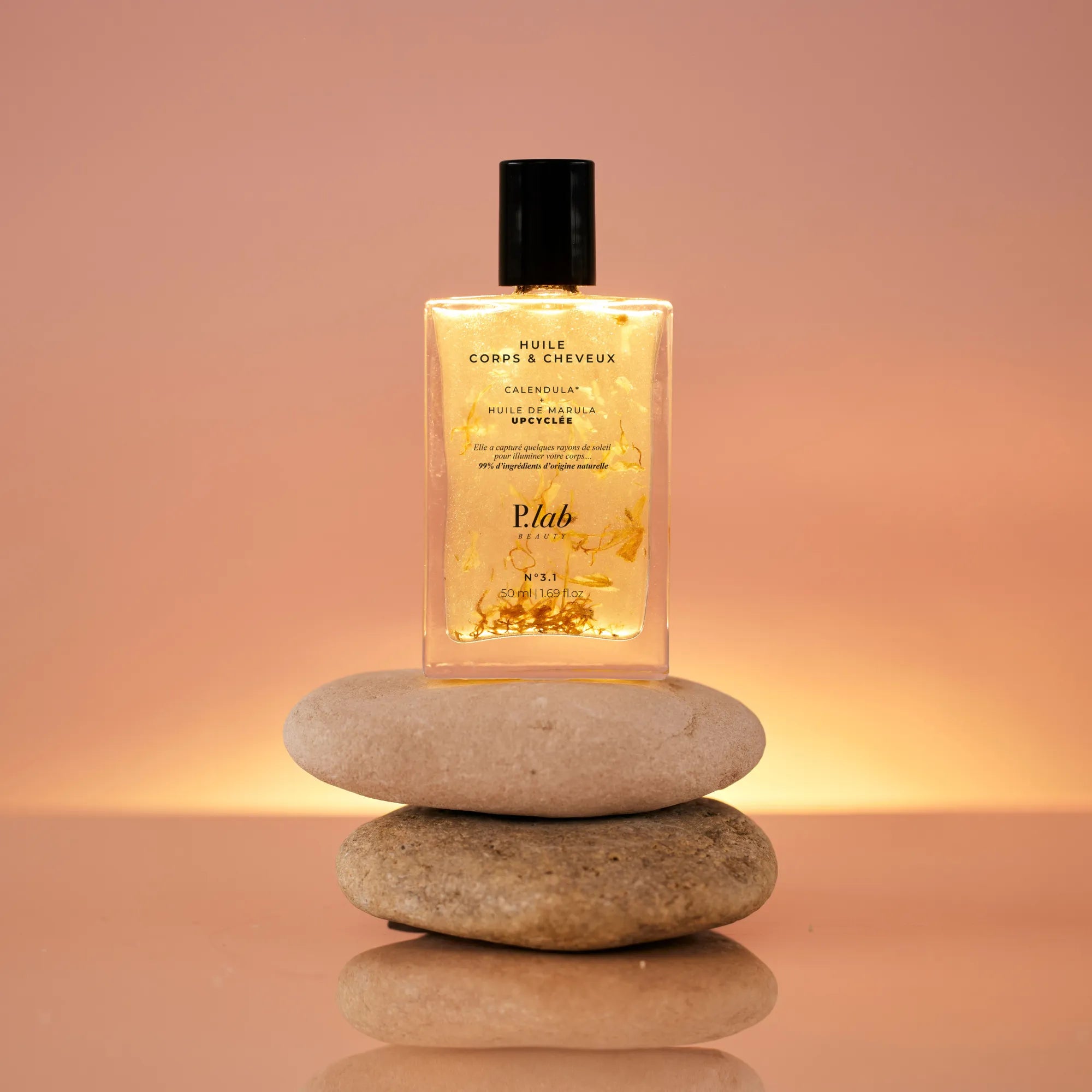 huile corps et cheveux jaune sur galets fond coucher de soleil