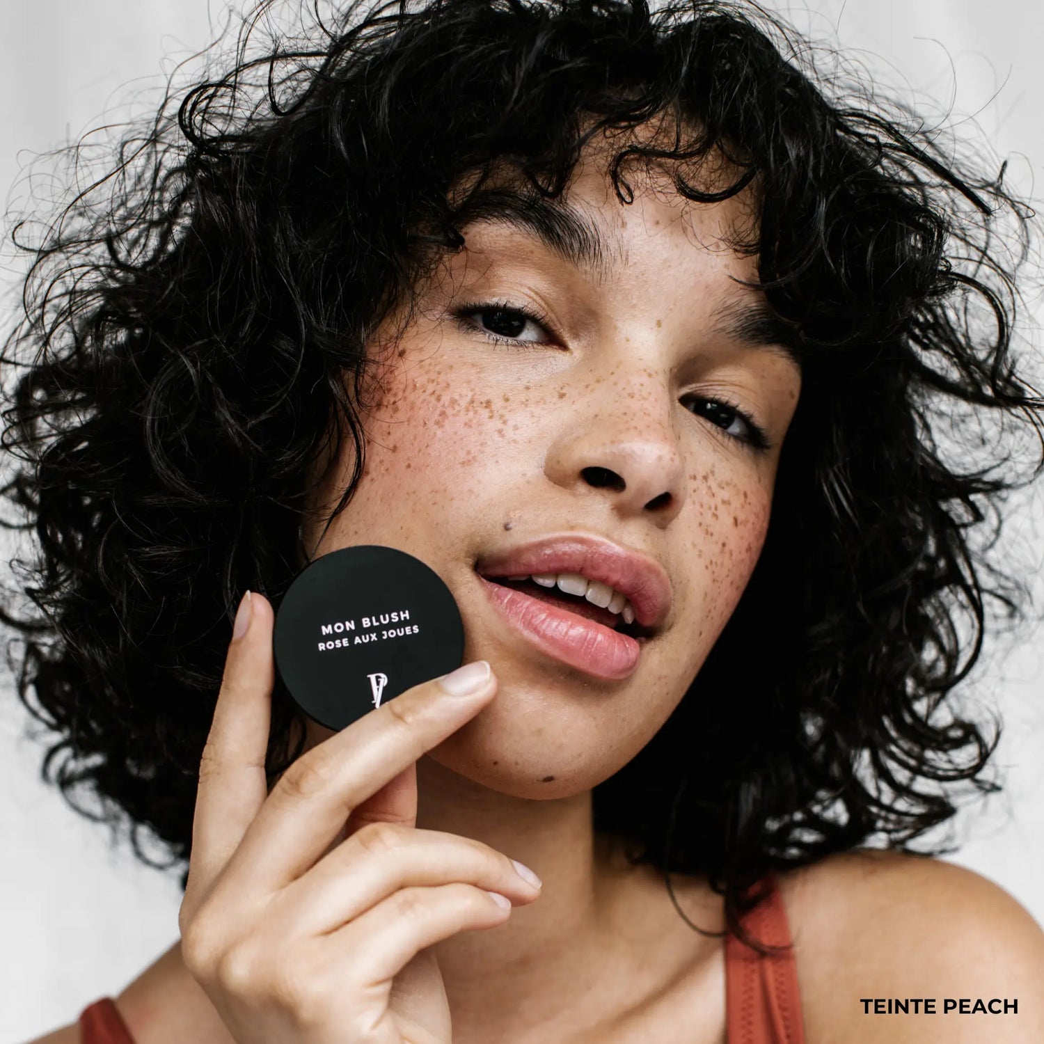 femme tenant blush crème devant son visage