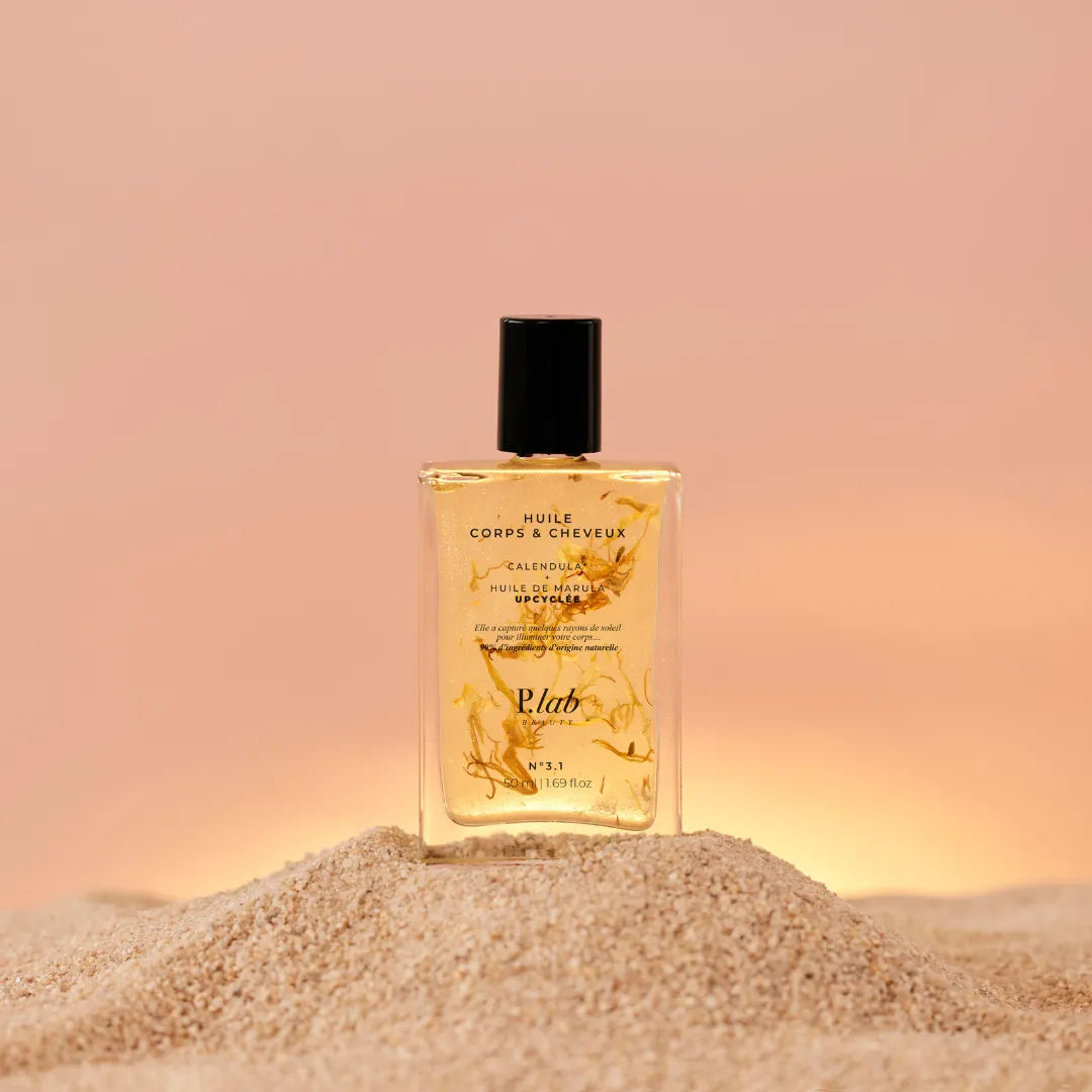 huile corps et cheveux jaune sur tas de sable fond coucher de soleil rose