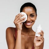 femme appliquant lotion visage sur coton